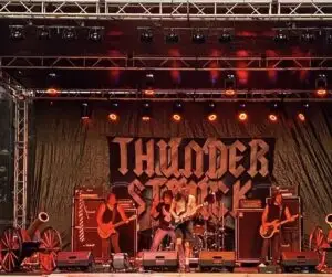 Outdoor concert stage with live band performance, truss lighting, and professional sound system