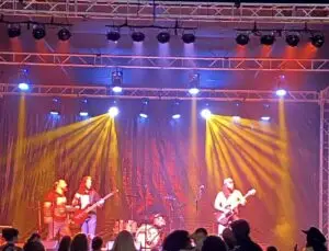 Concert stage with live band, professional truss lighting, and sound reinforcement